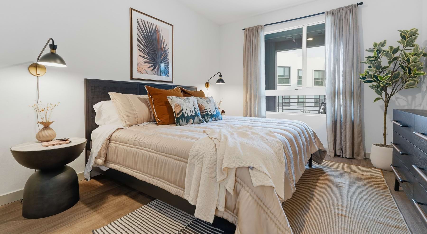 bedroom with bed lamps plant and windows