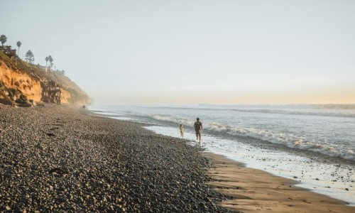 a person and a child walking on a beach